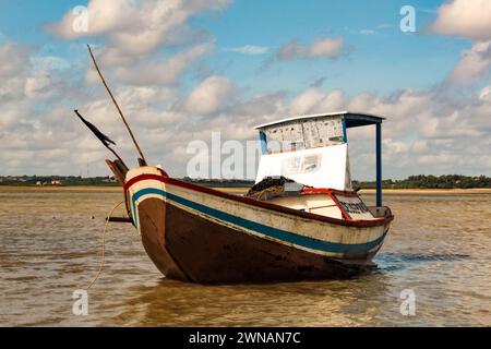 Beau et coloré petit bateau rustique en bois échouée, canoë de pêche motorisé utilisé pour la pêche en haute mer. Il y a un filet de pêche sur le pont Banque D'Images