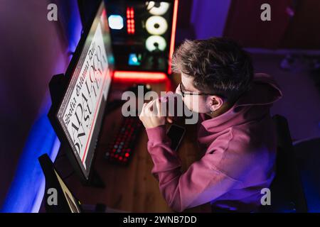 Graphiste en vêtements décontractés travaillant avec son nouveau projet dans sa chambre la nuit. Banque D'Images