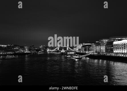 Puissant paysage nocturne lumineux et abstrait monochrome de la Tamise photographié depuis London Bridge et montrant Tower Bridge, Canary Wharf, Tooley Street, London Bridge Hospital, HMS Belfast, London Bridge City Pier et River Boats Banque D'Images