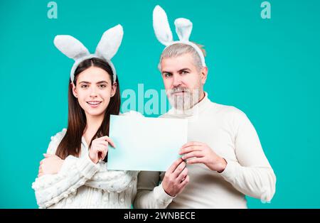 Le couple de Pâques tient un tableau blanc vierge pour votre texte. Portrait du couple de Pâques heureux. Banque D'Images