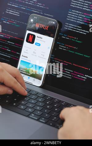 New York, États-Unis - 23 février 2024 : Code pour la nouvelle application Netflix dans l'écran d'ordinateur portable avec les mains sur le clavier Banque D'Images