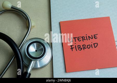 Concept de Fibroid utérin écrire sur des notes collantes avec stéthoscope isolé sur une table en bois. Banque D'Images