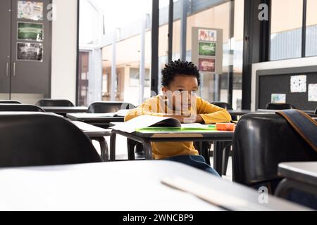 Garçon afro-américain est assis dans une salle de classe d'école, son expression pensive, avec un espace de copie Banque D'Images