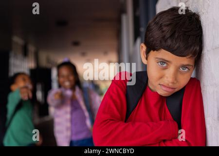 Garçon biracial s'appuie contre un mur blanc, l'air pensif, victime d'intimidation à l'école Banque D'Images