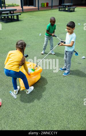 Les enfants ramassent la litière avec des grabbers dans une aire de jeux à l'école Banque D'Images