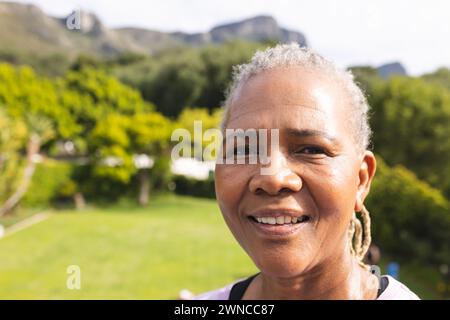 Femme biraciale senior avec les cheveux gris sourires à l'extérieur avec espace de copie Banque D'Images