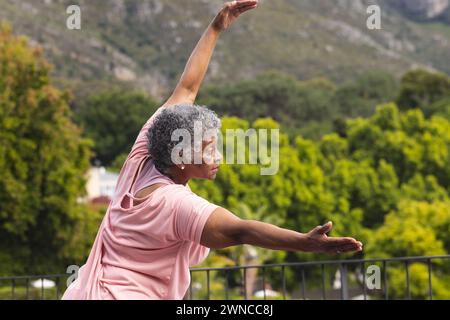 Femme biraciale senior avec les cheveux gris pratique le yoga à l'extérieur Banque D'Images