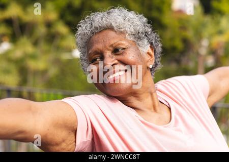 Femme biraciale senior avec les cheveux gris bouclés souriant à l'extérieur Banque D'Images
