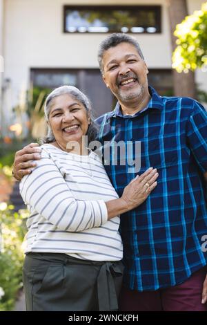 Couple biracial senior sourit chaleureusement, embrassant à l'extérieur Banque D'Images