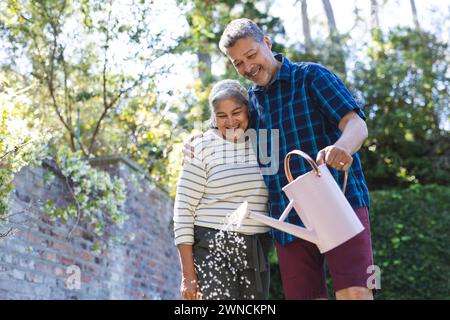 Femme biraciale senior et homme biracial partagent un moment joyeux jardinage à l'extérieur Banque D'Images