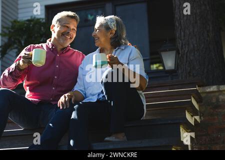 Femme biraciale senior et homme biracial profiter du café à l'extérieur Banque D'Images