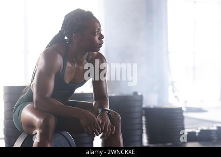 Athlète biracial dans la tenue de gym repose avec détermination, incarnant la force. Banque D'Images