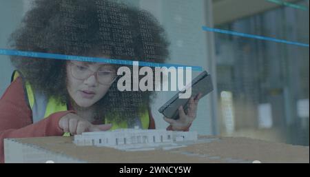 Image du traitement des données financières sur la femme biraciale vérifiant le modèle 3d dans le bureau Banque D'Images