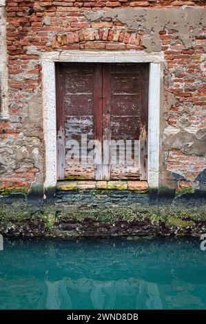 Vieille porte en bois menant à un canal à Venise Italie Banque D'Images