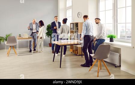 Groupe de collègues parlant les uns aux autres pendant la réunion d'affaires au bureau Banque D'Images