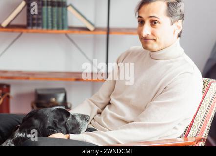 Portrait de deux amis inséparables. Le pointeur noir et blanc à poil court regarde attentivement le propriétaire qui est perdu dans ses pensées et le caresse. Banque D'Images