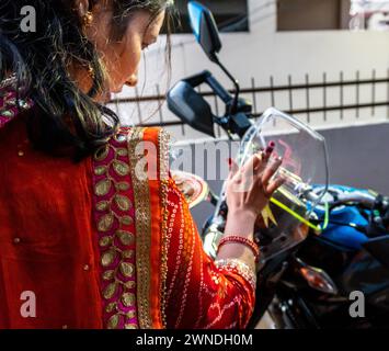 11 janvier 2024, Uttarakhand Inde. Jeune femme exécutant Pooja et rituels traditionnels sur un véhicule neuf pendant le Festival de Dhanteras, Banque D'Images