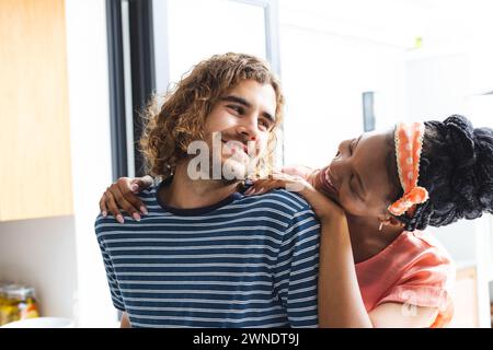 Couple diversifié partage un moment ludique dans un cadre de cuisine lumineux Banque D'Images