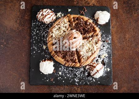 Gaufre chocoholic, recouverte de copeaux de lait et de chocolat blanc servie avec glace à la vanille et crème fraîche Banque D'Images