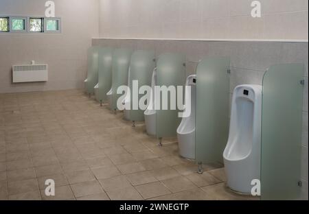 Rangée d'urinoirs séparés par des panneaux de verre dépoli dans les toilettes publiques des hommes en Corée du Sud Banque D'Images