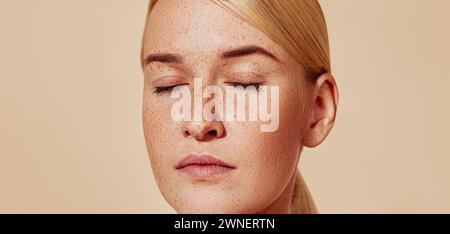 Gros plan en studio d'une jeune belle femme blonde avec des taches de rousseur. Cliché recadré d'une femelle à la peau lisse. Banque D'Images
