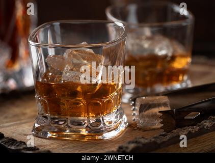 Deux verres de whisky avec de la glace sur plateau en bois rustique avec carafe dans le backgroound Banque D'Images