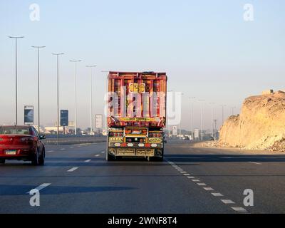 Le Caire, Égypte, 16 décembre 2023 : camion à plateau grand véhicule avec un conteneur d'expédition en acier, au Caire Suez voie spécifique, service d'expédition et de livraison Banque D'Images