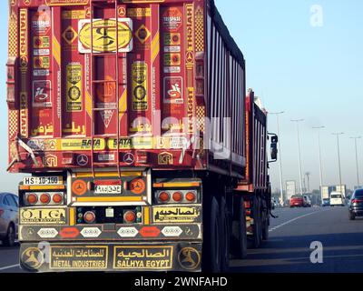 Le Caire, Égypte, 16 décembre 2023 : camion à plateau grand véhicule avec un conteneur d'expédition en acier, au Caire Suez voie spécifique, service d'expédition et de livraison Banque D'Images