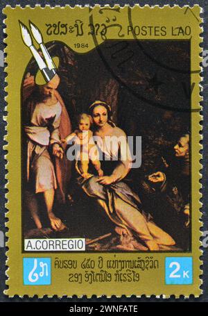 Timbre-poste oblitéré imprimé par le Laos, qui montre le repos de peinture sur le vol vers l'Egypte avec Saint François par Correggio, vers 1984. Banque D'Images