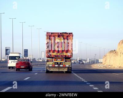 Le Caire, Égypte, 16 décembre 2023 : camion à plateau grand véhicule avec un conteneur d'expédition en acier, au Caire Suez voie spécifique, service d'expédition et de livraison Banque D'Images