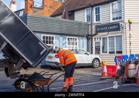 Ouvrier manuel masculin pelletant le tarmac pour une réparation de route à Rayleigh sur London Hill. Banque D'Images