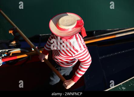 Gondolier vénitien avec la chemise rayée rouge et blanche tout en ramant la gondole dans le Grand canal à Venise Banque D'Images