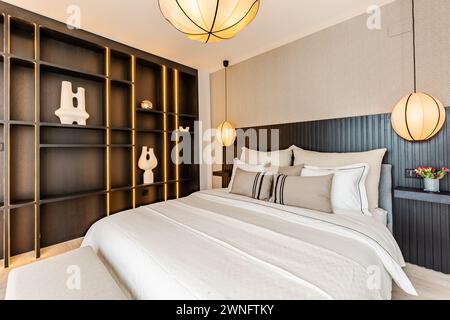 une image d'un lit fraîchement fait à côté d'une vitrine équipée noire dans la chambre principale de l'immobilier méditerranéen Banque D'Images