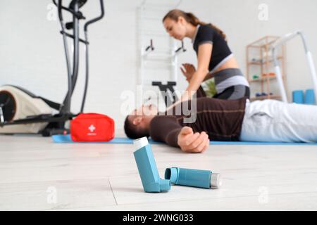 Inhalateurs d'asthme et entraîneur donnant à l'homme les premiers soins dans le gymnase, gros plan Banque D'Images