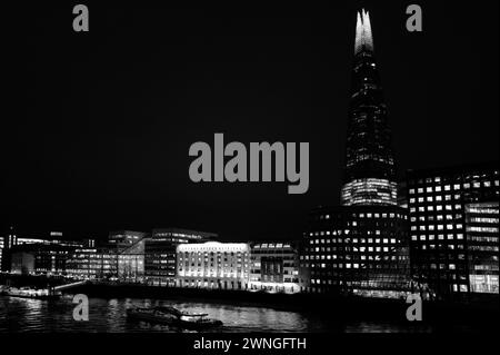 Puissant paysage de nuit lumineux et abstrait monochrome du Shard et de la Tamise photographié depuis le London Bridge et montrant Tooley Street, l'hôpital London Bridge, le HMS Belfast, la jetée de London Bridge City et les bateaux fluviaux Banque D'Images