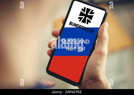 2 mars 2024 : la Russie écoute en personne tenant le téléphone avec le drapeau russe et le logo de la Bundeswehr de l'Allemagne. Taurus écoute scandale de la Bundeswehr allemande par les Russes. PHOTOMONTAGE *** Russland hört mit person hält Telefon mit Russland Fahne und Bundeswehr logo von Deutschland in der Hand. Taurus Abhörskandal der deutschen Bundeswehr durch den Russen. FOTOMONTAGE Banque D'Images