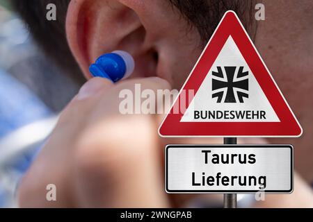 2 mars 2024 : scandale des écoutes téléphoniques de la Bundeswehr depuis la Russie. Homme avec un casque et un signe avec le logo Bundeswehr et l'inscription : Taurus Delivery. PHOTOMONTAGE *** Abhörskandal der Deutschen Bundeswehr von Russland. Mann mit Kopfhörer und ein Schild mit Bundeswehr logo und der Aufschrift : Taurus Lieferung. FOTOMONTAGE Banque D'Images