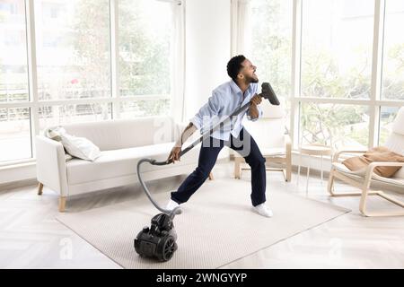 Excité drôle jeune homme de propriétaire africain chantant à hoover Banque D'Images