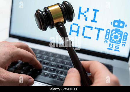 2 mars 2024 : image symbolique de la régulation de l'intelligence artificielle, homme assis devant un ordinateur portable avec un marteau de juge, un robot à l'écran et les mots : Ki-Act. PHOTOMONTAGE *** Symbolbild Regulierung von Künstlicher Intelligenz, Mann sitzt mit Richterhammer vor Laptop, auf dem Bildschirm ein Roboter und der Schriftzug : Ki-Act. FOTOMONTAGE Banque D'Images