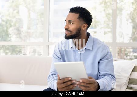 Positif réfléchi jeune homme afro-américain utilisant la tablette numérique Banque D'Images