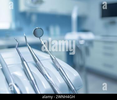 Une vue détaillée de divers instruments dentaires placés sur une table dans une salle clinique, prêts à l'emploi. Banque D'Images