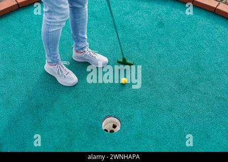 Golfeur jouant à l'aventure ou au mini-golf et essayant de mettre la balle dans le trou. Activités sportives et de loisirs Banque D'Images