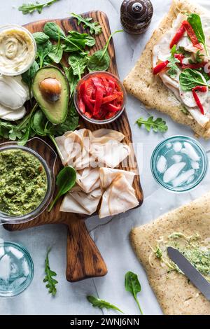 Ingrédients frais sur une planche de bois pour faire des wraps de dinde au pesto deli. Banque D'Images