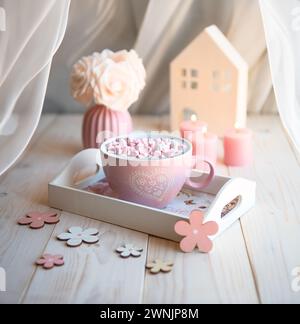 Une grande tasse rose de délicieux chocolat chaud avec des guimauves sur un fond confortable. Banque D'Images