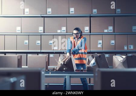 Ouvrière rebelle agressive brisant des boîtes au travail, elle est frustrée et en colère Banque D'Images