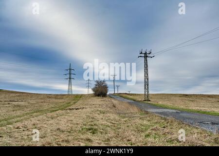 Anciennes et nouvelles lignes électriques du réseau électrique et tours de transmission le long de la route rurale à travers les champs agricoles. Différents pylônes électriques à haute tension. Banque D'Images