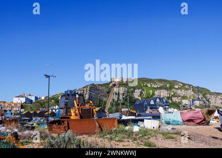 Tracteur bulldozer rouillé et petits bateaux de pêche traditionnels en bois échoués remorqués sur la plage de galets du stade à Hastings, East Sussex, Angleterre Banque D'Images