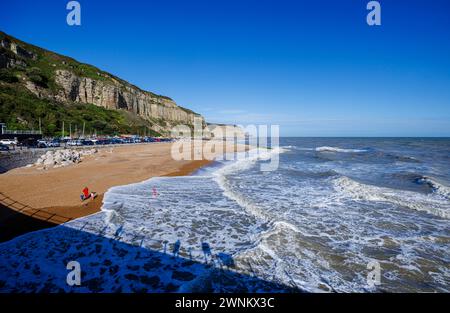 Vue panoramique des vagues qui se brisent sur la plage de galets de Rock-a-Nore et les falaises sur la côte à Hastings, East Sussex, Angleterre par une journée ensoleillée Banque D'Images