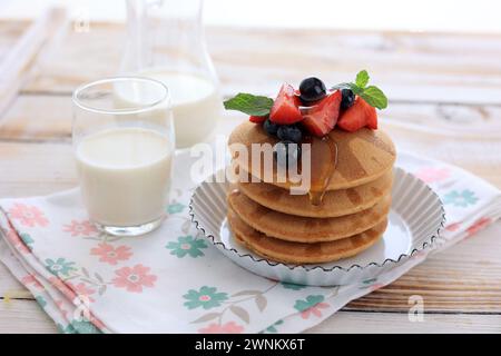 Gaufres empilées avec sirop d'érable et garniture de baies, servies avec du lait Banque D'Images