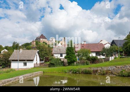 Vue d'un petit village avec un château en arrière-plan et un étang en premier plan sous un ciel nuageux, Château de Lipnice, Lipnice nad Sazavou Banque D'Images